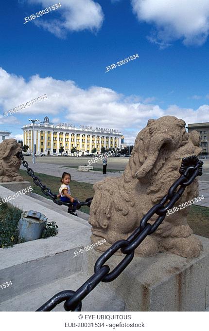 Sukhbaatar square with small girl sitting on chainlink fence around steps in foreground