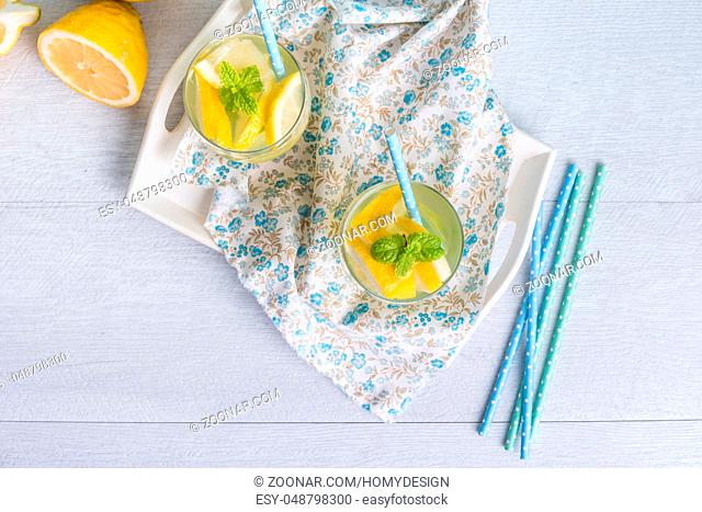 Summer citrus fruits drink on wooden background. Detox citrus infused flavored water. Refreshing summer homemade cocktail with lemon