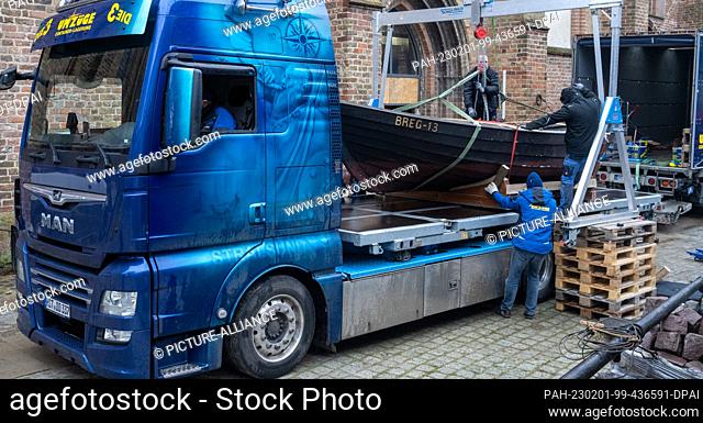 01 February 2023, Mecklenburg-Western Pomerania, Stralsund: Employees of a moving company load an almost seven-meter-long fishing boat ""Erika"" in the...