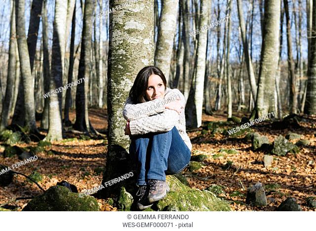 Woman sitting on a rock in a beech forest