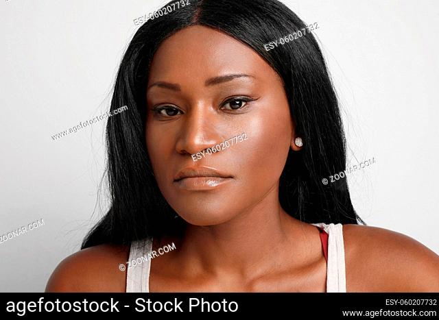 Portrait of young black woman looking at the camera, isolated over white wall. High quality photo