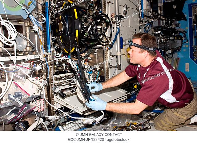 NASA astronaut Ron Garan, Expedition 27 flight engineer, services the Combustion Integrated Rack (CIR) Multi-user Drop Combustion Apparatus (MDCA) in the...