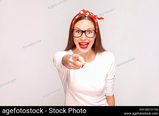 its it you? pointing finger at camera. portrait of beautiful emotional young woman in white t-shirt with freckles, black glasses, red lips and head band