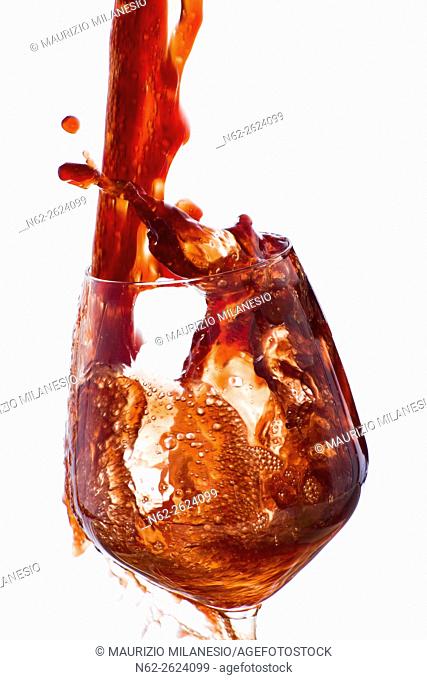 Drink, vigorously poured overflowing splashing from a wine glass, on a white background