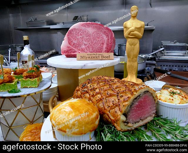 08 March 2023, USA, Los Angeles: Miyazaki beef (back) and filet Wellington lies next to a gold-colored miniature Oscar. Star chef Wolfgang Puck serves up for...