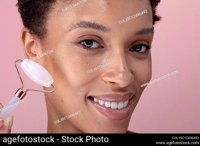 Close-up of smiling woman with facial roller