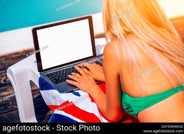 Young Blondie Woman Is Laying Near The Pool And Surfing The Internet On Her Laptop.Deck Chair.Green Bikini
