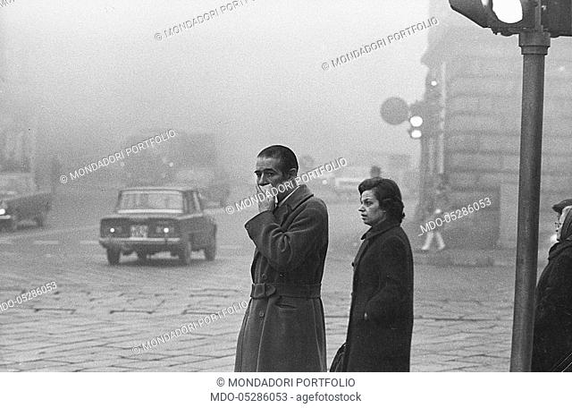 A man protecting himself from the pollution with an handkerchief in a foggy Milan. Milan, 1969
