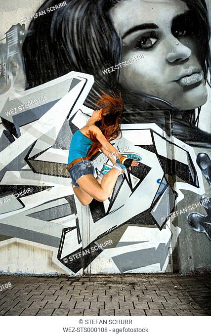 Female hip hop dancer dancing in front of airbrushed wall