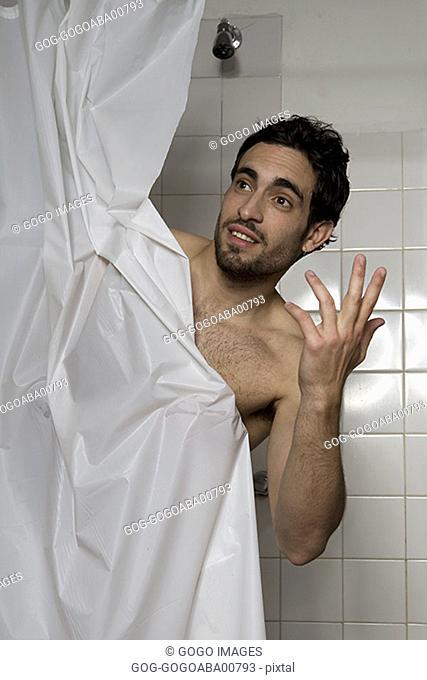 Man looking out from behind shower curtain