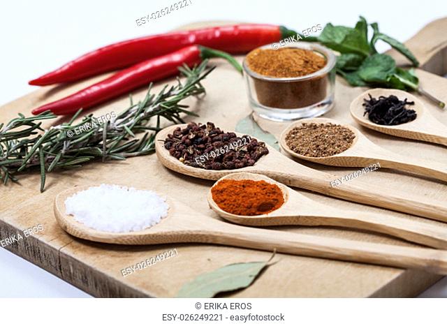 Various colorful spices on kitchen spoons over grunge wooden cuttingtable