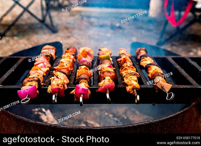 Selective focus of large home made barbecue with six pieces of skewers on top of the grill filled with meat and healthy vegetables