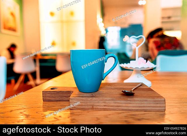 Hot cappuccino coffee in coffee shop on wooden table, close angle