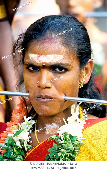 Woman piercing iron rod through cheeks discharging vow in Mariamman festival ; Tamil Nadu ; India NO MR