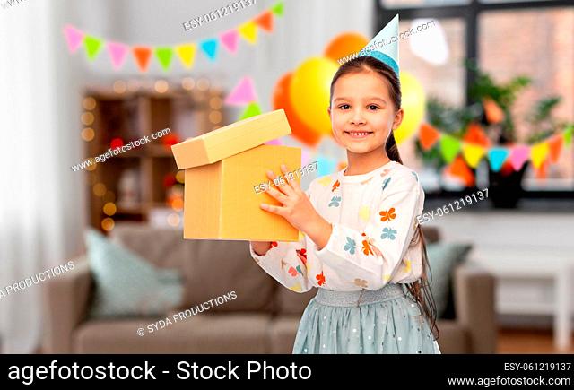 smiling girl in party hat opening birthday gift