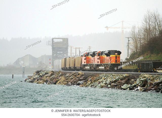 A BNSF train in a rainstorm at Chambers Bay near Sunnyside Beach Park, Tacoma, Washington, USA