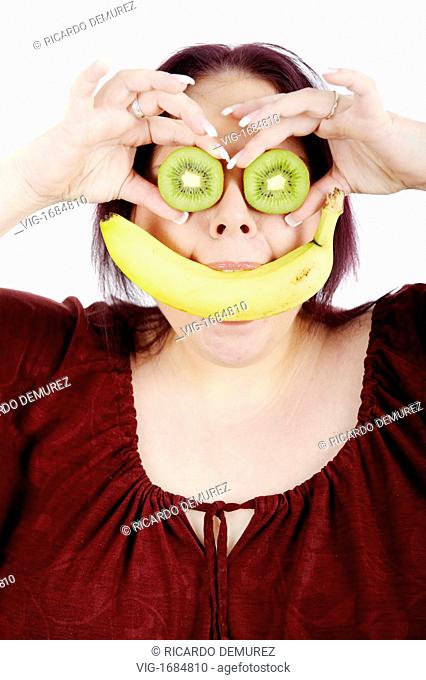 AUSTRIA , VIENNA , 11.01.2009, Young fat woman with a banana in her mouth and kiwis in front of her eyes - Vienna, Vienna, AUSTRIA, 11/01/2009