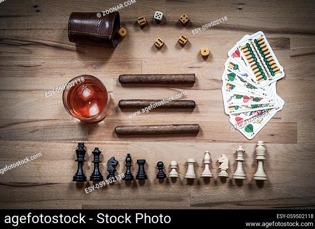 Wuerfelspiel, Schachfiguren, Spielkarten mit Zigarren und alkoholischem Getraenk in der Draufsicht fotografiert