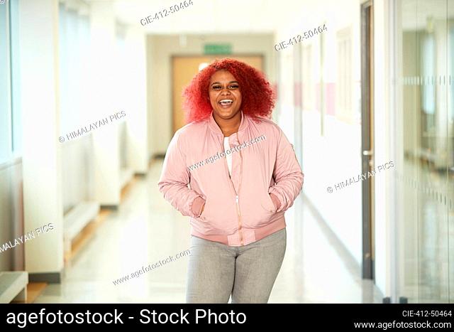 Portrait enthusiastic female high school student in corridor