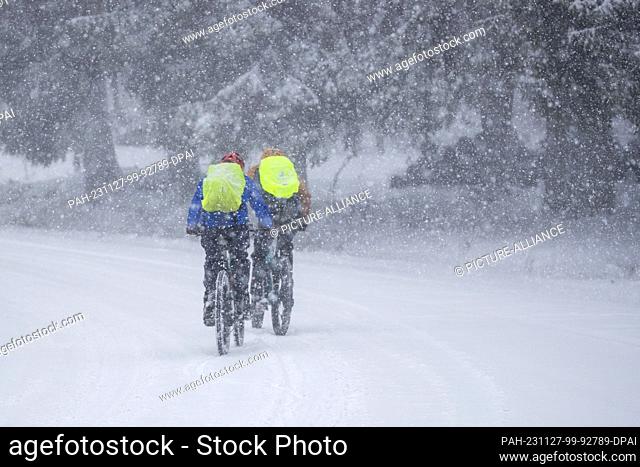 27 November 2023, Hesse, Feldberg: Cyclists are out and about on the Großer Feldberg in the Taunus in snowfall. Photo: Helmut Fricke/dpa