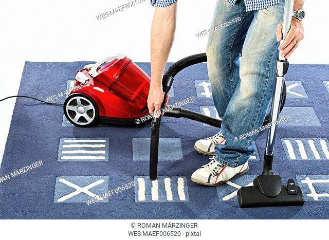 Mature man cleaning carpet with vaccuum cleaner