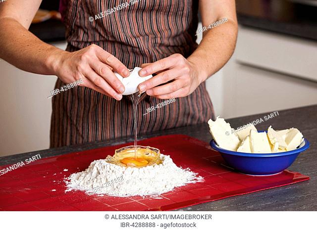 Woman breaking egg into flour