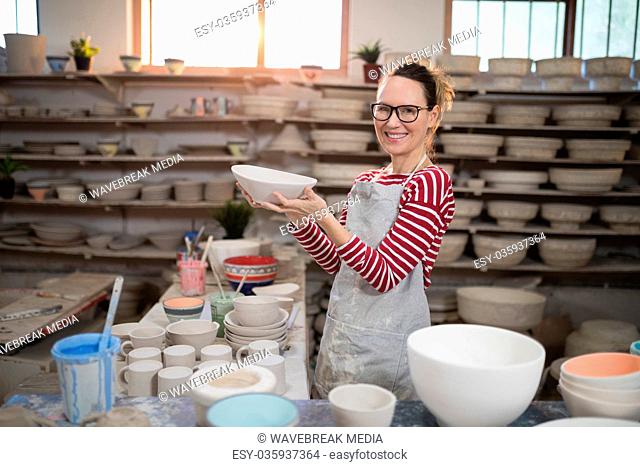 Portrait of female potter holding bowl