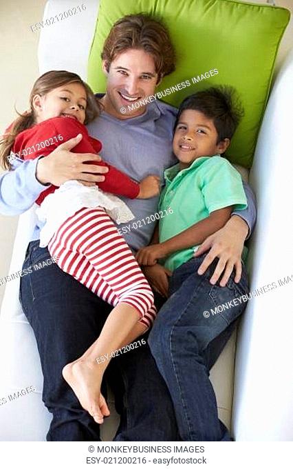 Overhead View Of Father And Children Relaxing On Sofa
