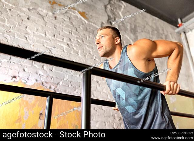 man doing triceps dip on parallel bars in gym