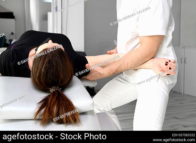 Male therapist giving massage to relief shoulder pain to a female patient in physiotheraphy clinic. High quality photo