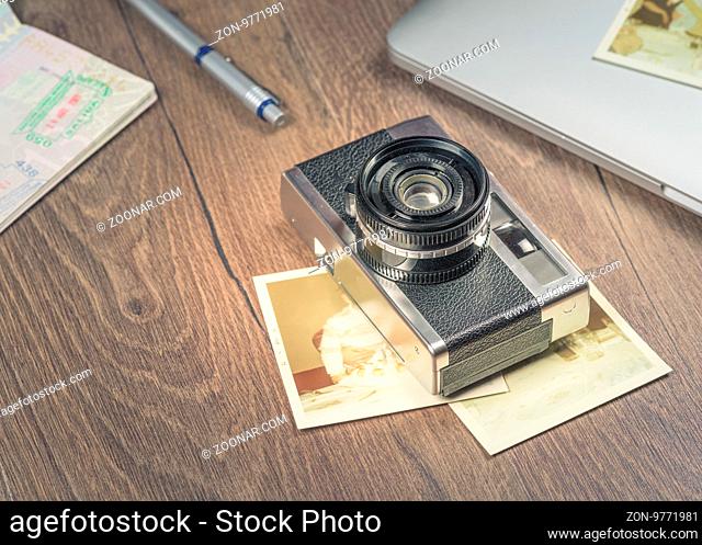 Vintage image with old Camera, old photo, laptop, pen and passport on wood table