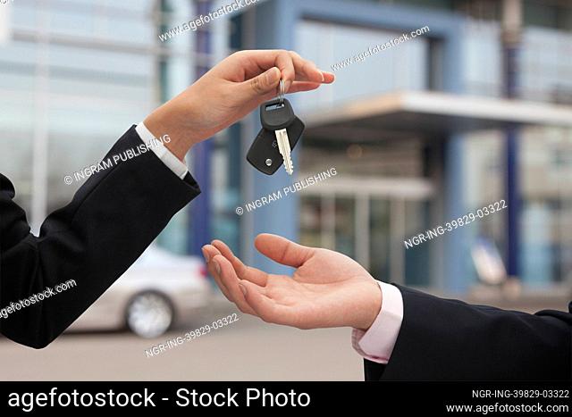 Salesman handing over car keys, close up on hands