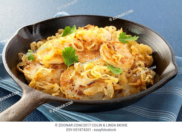 A classic French vegetable dish, Lyonnaise potatoes, sliced potato fried with onion, in a cast iron skillet