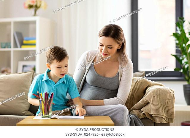 pregnant mother and son with workbook at home