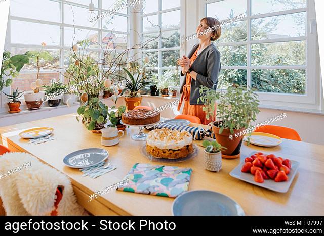 Woman smiling while standing by dining table at home