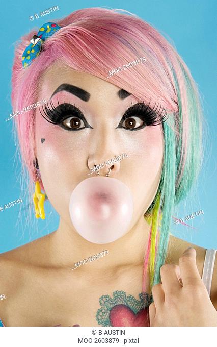 Portrait of young woman blowing bubble gum