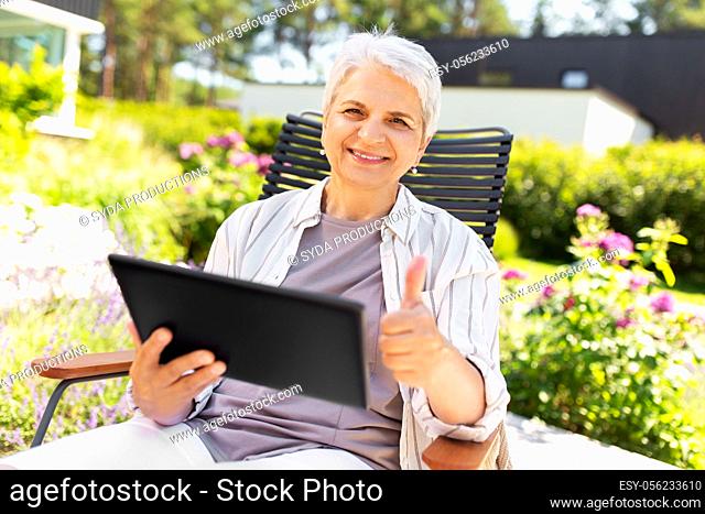 happy senior woman with tablet pc at summer garden