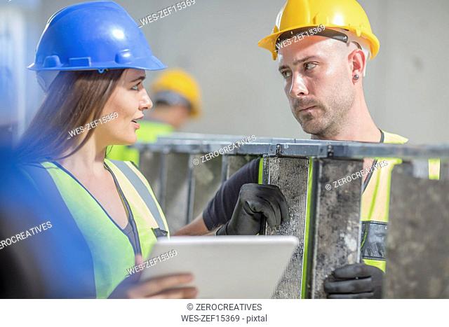 Woman with tablet talking to man with ladder on construction site