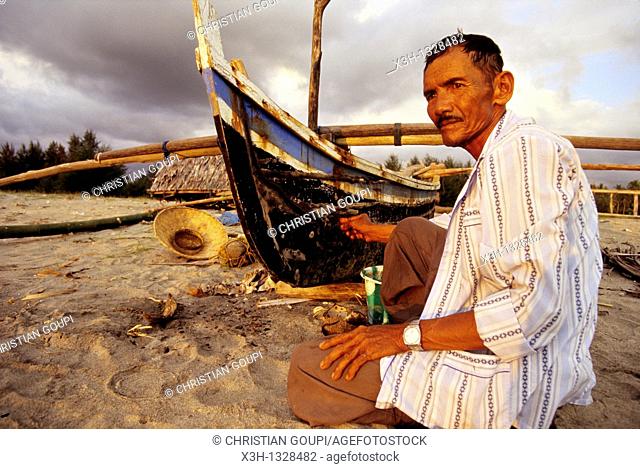 old man painting a boat on the Pariaman's beach, Sumatra island, Republic of Indonesia, Southeast Asia and Oceania