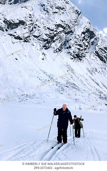 Two men nordic skiing in mountainous glacial valley, Jostedalsbreen, Norway