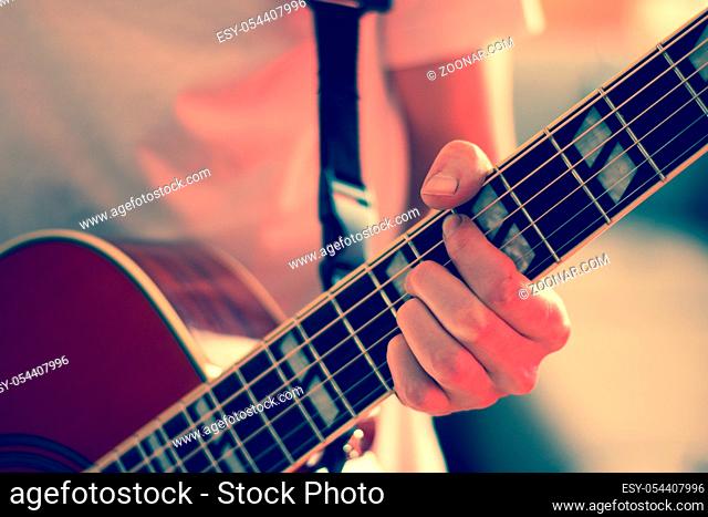 Young man playing a sunburst western guitar: cut out, blurry
