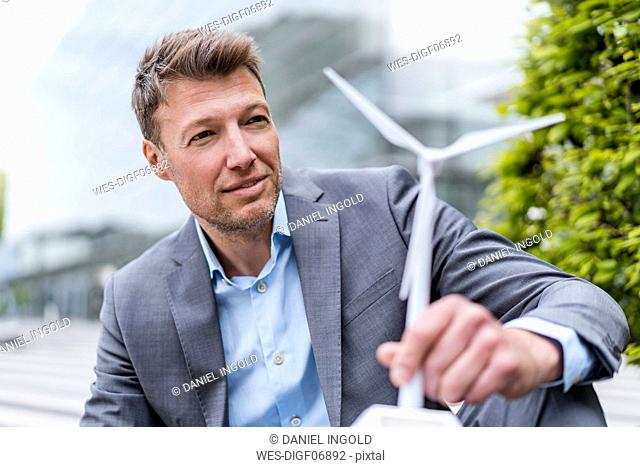 Businessman with wind turbine model outdoors
