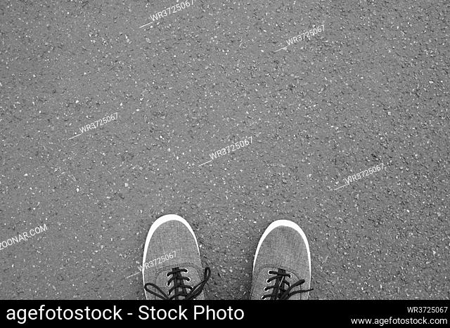 feet in canvas shoes standing on street - foot selfie from personal perspective point of view - asphalt background with copy space