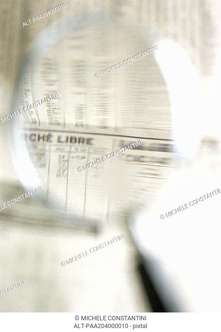 Financial information in newspaper, seen through magnifying glass, close-up