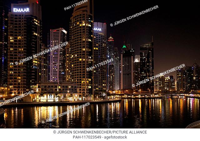 The shore area in front of the nocturnal skyline at Marina Bay is illuminated in an atmospheric way. The illuminated skyscrapers belong to the flair of the...