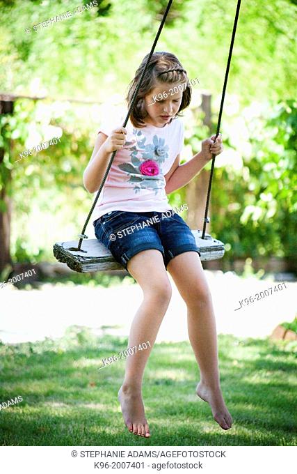 young girl swinging in beautiful greenery