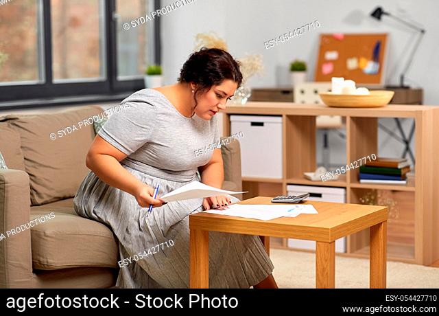 woman with bills or papers and calculator at home