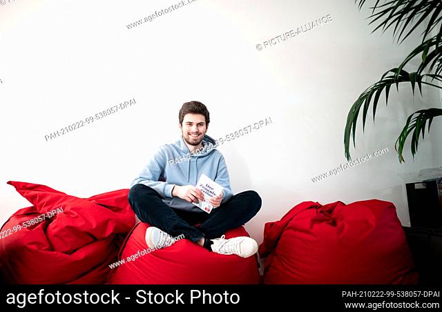 19 February 2021, North Rhine-Westphalia, Duesseldorf: Student and bestselling author Tim Nießner sits on a beanbag with his new book ""Der Zeugnisretter""