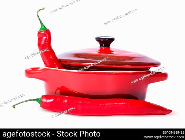Two red chili peppers and saucepan with lid isolated on white background
