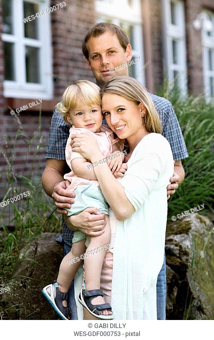 Parents with their little son in front of the house